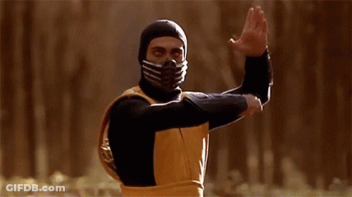 A Man Wearing A Mask And A Yellow Vest Is Standing In A Forest GIF