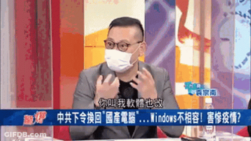 A Man Wearing A Mask And Glasses Is Sitting At A Table With Chinese Writing On The Screen Behind Him GIF