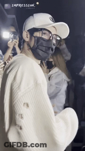 A Man Wearing A Mask And Glasses Is Standing In Front Of A Crowd With The Word Impression Above Him GIF