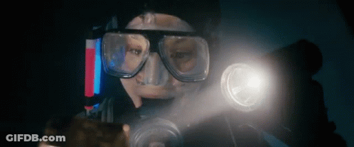 A Man Wearing A Mask And Goggles Is Holding A Flashlight In His Hand . GIF