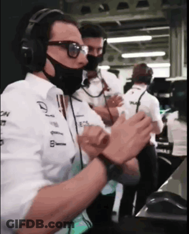 A Man Wearing A Mask And Headphones Is Clapping His Hands In A Garage . GIF