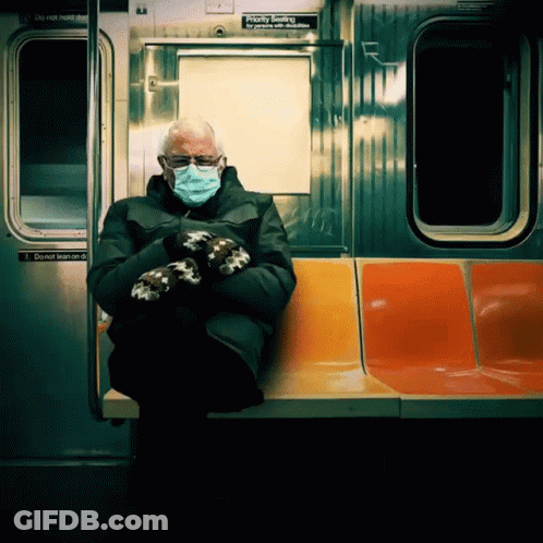 A Man Wearing A Mask And Mittens Sits On A Subway Train GIF