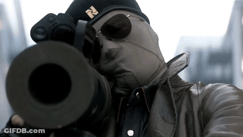 A Man Wearing A Mask And Sunglasses Is Aiming A Gun GIF