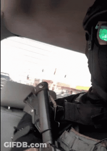 A Man Wearing A Mask And Sunglasses Is Holding A Gun In His Hand GIF