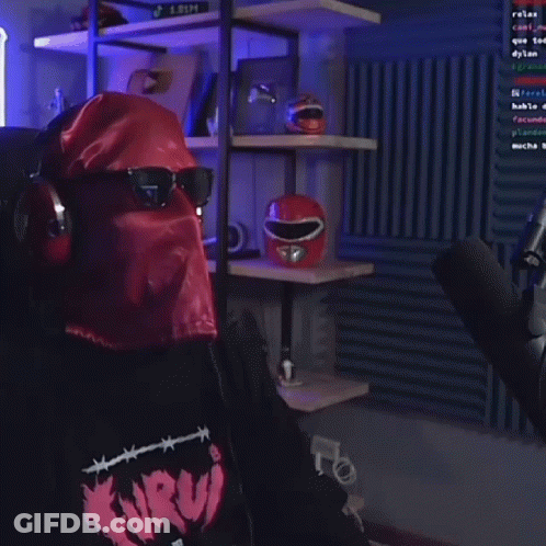 A Man Wearing A Mask And Sunglasses Is Holding A Microphone In A Room . GIF