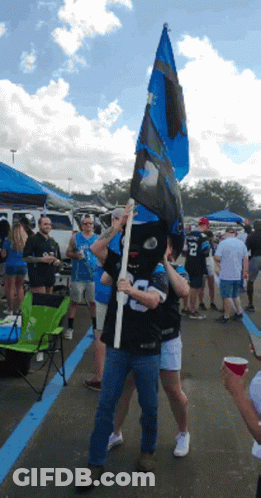 A Man Wearing A Mask Holds A Flag With A Number 8 On It GIF