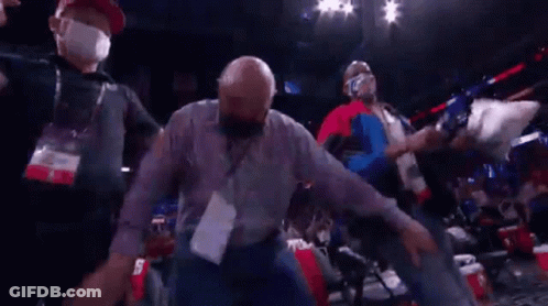 A Man Wearing A Mask Is Being Escorted Out Of A Stadium . GIF