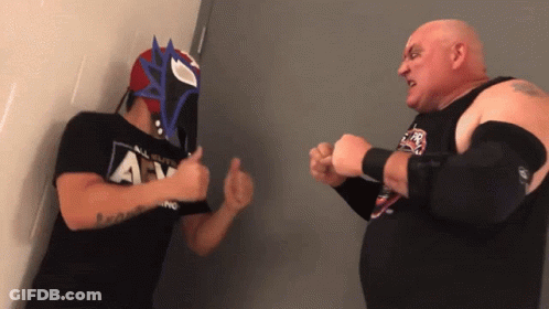 A Man Wearing A Mask Is Giving A Thumbs Up To Another Man Wearing An All Elite Wrestling Shirt GIF