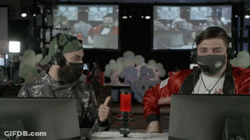 A Man Wearing A Mask Is Giving A Thumbs Up While Sitting In Front Of A Microphone GIF