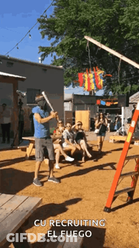A Man Wearing A Mask Is Holding A Bat In Front Of A Group Of People With The Words Cu Recruiting El Fuego Above Him GIF