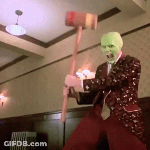 A Man Wearing A Mask Is Holding A Hammer In His Hand . GIF