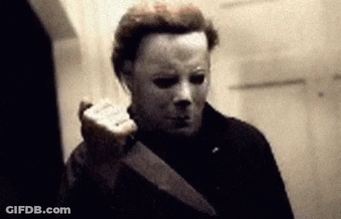 A Man Wearing A Mask Is Holding A Knife In His Hand . GIF