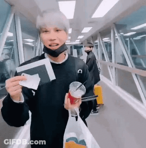 A Man Wearing A Mask Is Holding A Passport And A Cup Of Coffee . GIF