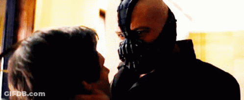 A Man Wearing A Mask Is Kissing Another Man On The Cheek . GIF