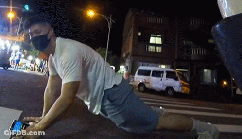 A Man Wearing A Mask Is Laying On The Ground Using His Phone GIF