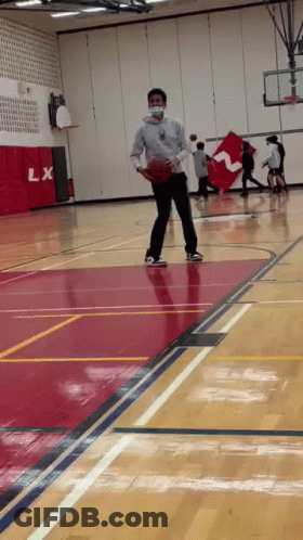 A Man Wearing A Mask Is Playing Basketball On A Court . GIF