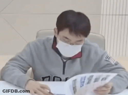 A Man Wearing A Mask Is Reading A Book . GIF