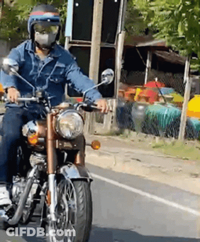 A Man Wearing A Mask Is Riding A Motorcycle GIF