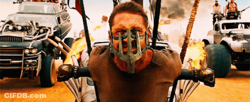 A Man Wearing A Mask Is Sitting In Front Of A Row Of Cars GIF