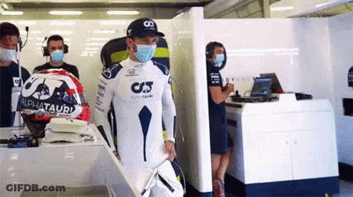A Man Wearing A Mask Is Standing In A Garage With A Helmet . GIF