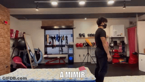 A Man Wearing A Mask Is Standing In A Gym With The Words A Mimir Behind Him GIF