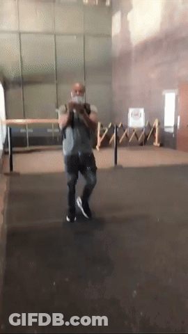 A Man Wearing A Mask Is Standing In A Room With A Fence In The Background GIF