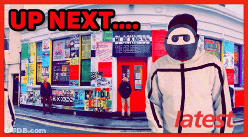 A Man Wearing A Mask Is Standing In Front Of A Building That Says Up Next GIF