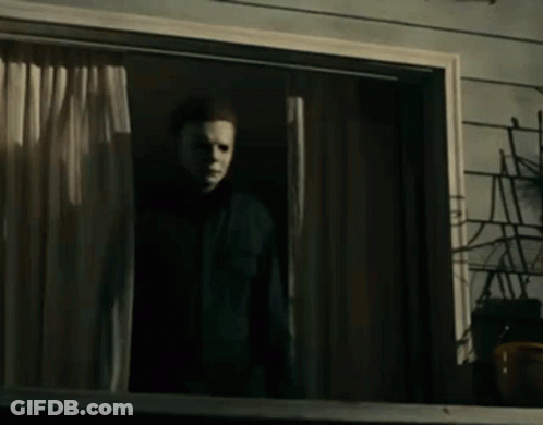A Man Wearing A Mask Is Standing In Front Of A Window . GIF