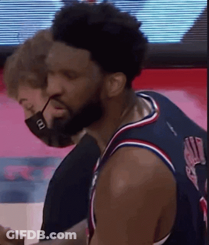 A Man Wearing A Mask Is Standing Next To A Basketball Player Wearing A Jersey . GIF