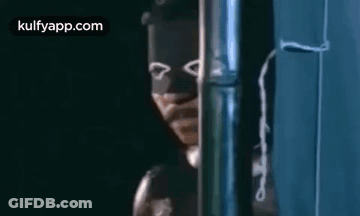 A Man Wearing A Mask Is Standing Next To A Pipe . GIF