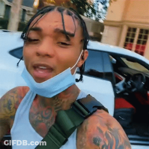 A Man Wearing A Mask Is Standing Next To A White Car . GIF