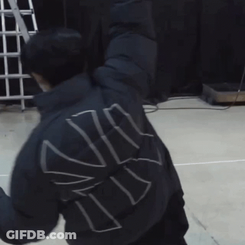 A Man Wearing A Mask Is Stretching His Arms While Another Man Looks On GIF