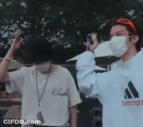 A Man Wearing A Mask Is Taking A Picture Of Another Man . GIF