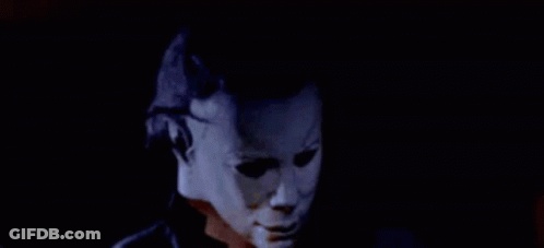 A Man Wearing A Mask Is Talking On A Cell Phone In The Dark . GIF