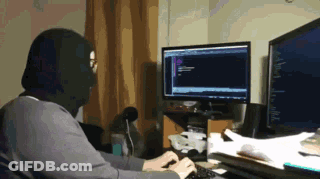 A Man Wearing A Mask Is Typing On A Keyboard In Front Of A Computer Monitor GIF