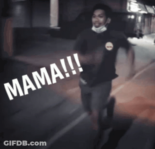 A Man Wearing A Mask Is Walking Down A Street With The Word Mama Written On The Ground GIF