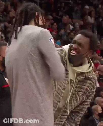 A Man Wearing A Mask Laughs With Another Man In A Crowd GIF
