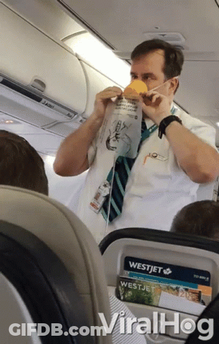 A Man Wearing A Mask On An Airplane With A Westjet Advertisement GIF