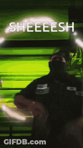 A Man Wearing A Mask Stands In Front Of A Green Background That Says Sheeesh GIF