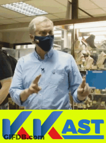 A Man Wearing A Mask Stands In Front Of A Sign That Says Kvast GIF