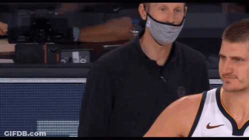 A Man Wearing A Mask Stands Next To A Man Wearing A Nike Shirt GIF