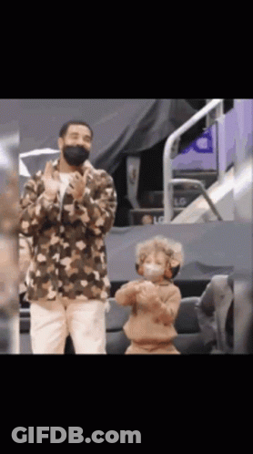 A Man Wearing A Mask Stands Next To A Young Boy Wearing A Mask GIF