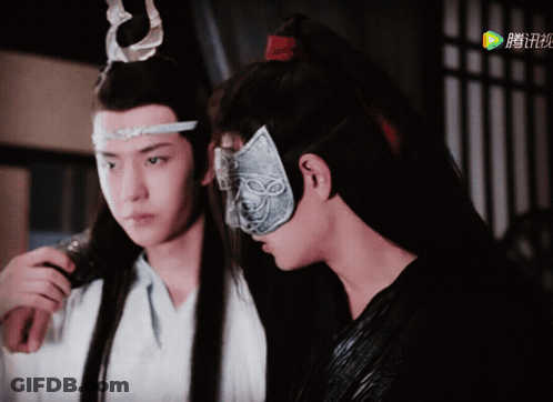 A Man Wearing A Mask Stands Next To Another Man In A White Shirt GIF