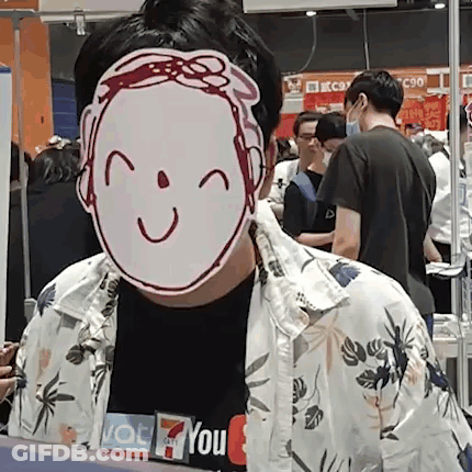 A Man Wearing A Mask With A Smile On It Is Standing In Front Of A Crowd Of People . GIF