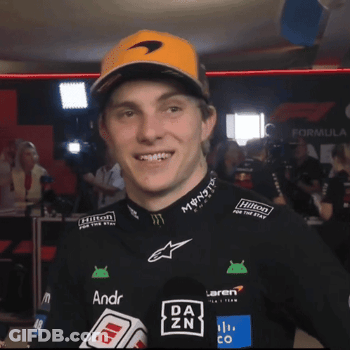 A Man Wearing A Mclaren Shirt And A Hilton Hat GIF