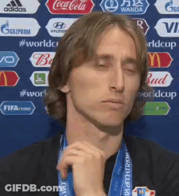 A Man Wearing A Medal Around His Neck Is Making A Funny Face With His Eyes Closed . GIF