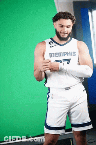 A Man Wearing A Memphis Jersey And Shorts Stands In Front Of A Green Screen GIF