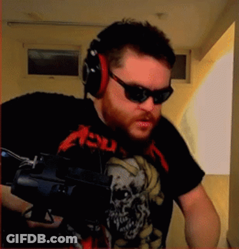 A Man Wearing A Metallica Shirt And Headphones Holds A Gun GIF
