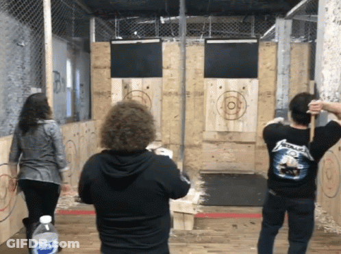 A Man Wearing A Metallica Shirt Throws An Axe GIF