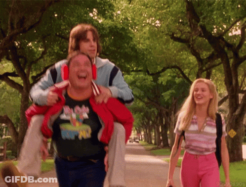 A Man Wearing A Mickey Mouse Shirt Is Carrying Another Man GIF